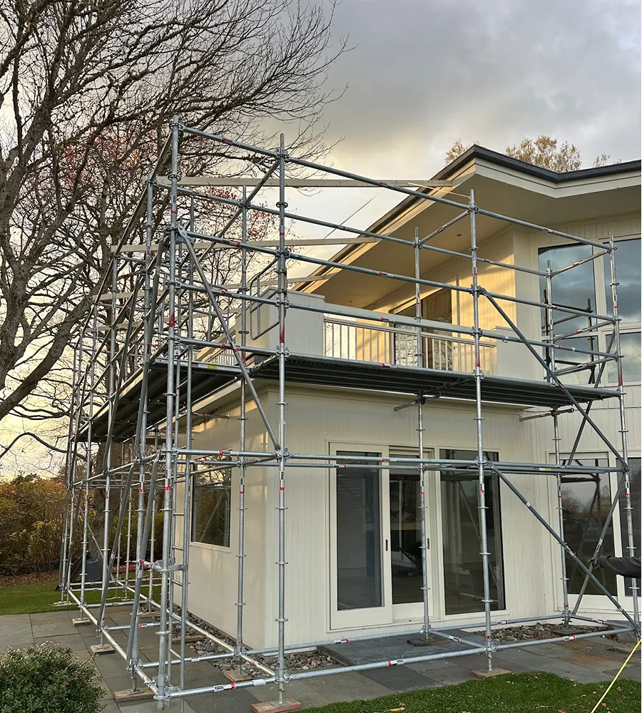 System scaffolding with multiple lift levels built around a New England home under renovation
