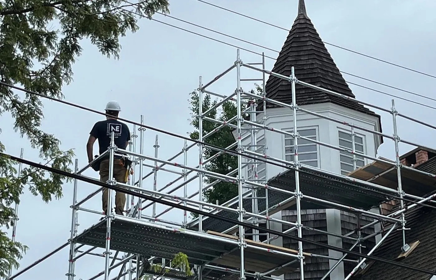 Scaffold builder in a hard hat standing on a platform beside a building turret